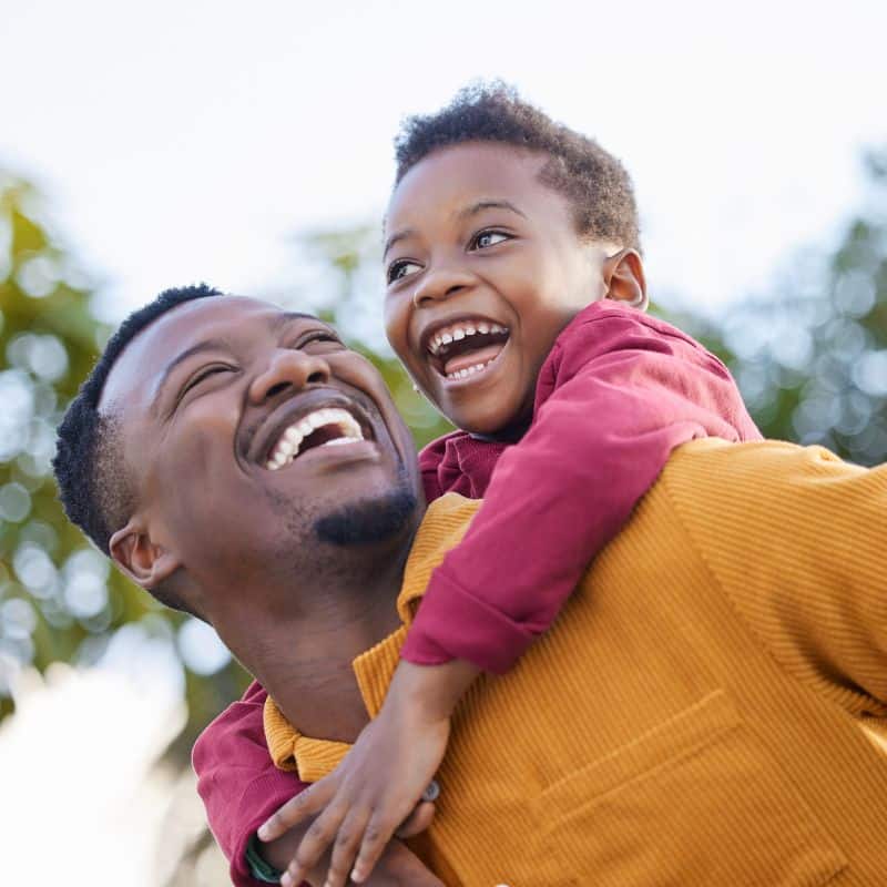 Father and child smiling together outdoors representing family dental care in richmond, va