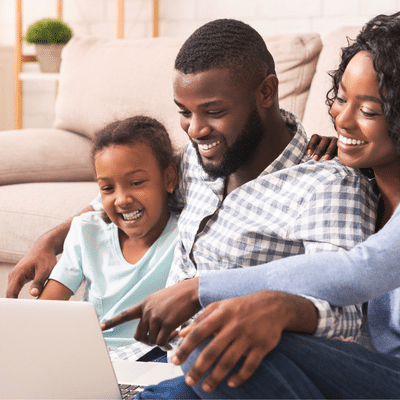 Family smiling while working on a laptop, representing new website