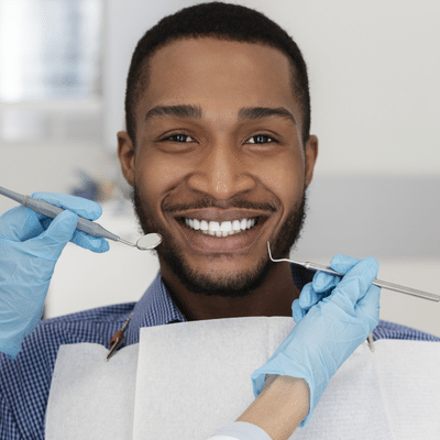 Man smiling while receiving dental work, representing why routine dental cleanings are important