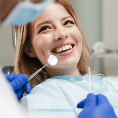 Woman smiling while receiving dental treatment, representing first dental visit
