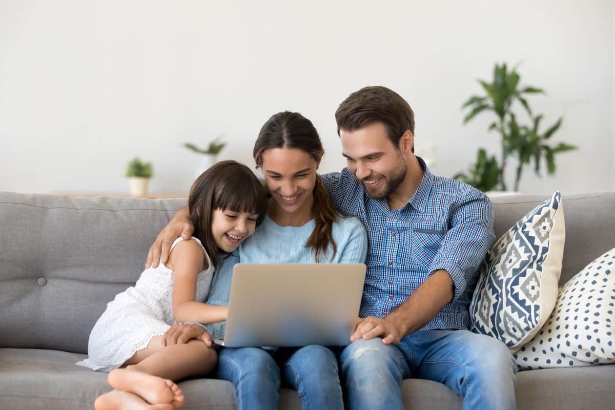 Happy family looking at a laptop together representing positive patient testimonials at tuckahoe creek dental in richmond, va.
