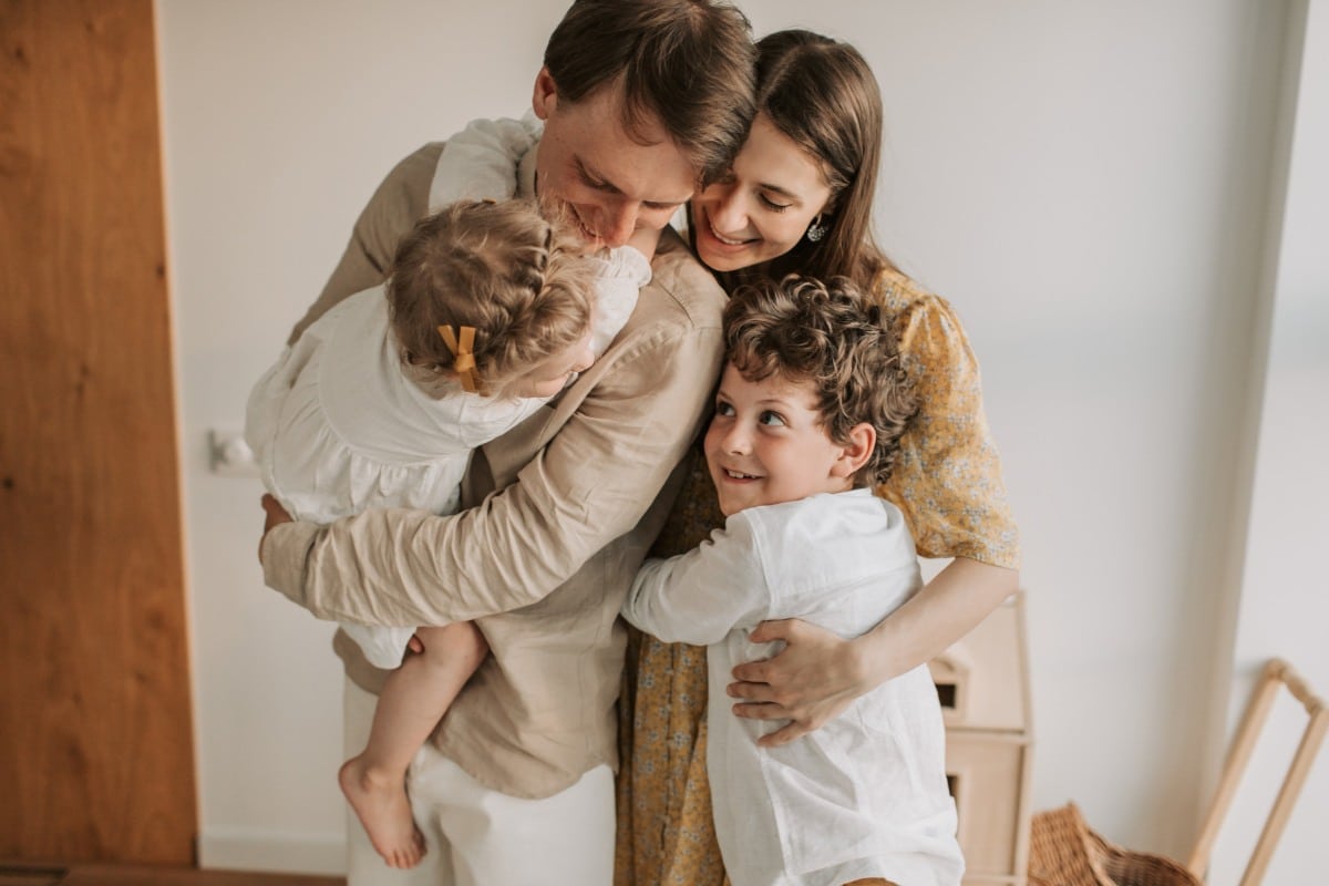 Happy family embracing at home representing family dental care in henrico and richmond va and family dentistry benefits.
