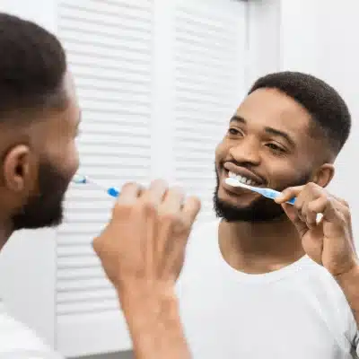 Tooth decay and oral hygiene 3 Man brushing his teeth in front of a mirror, representing how oral hygiene prevents tooth decay
